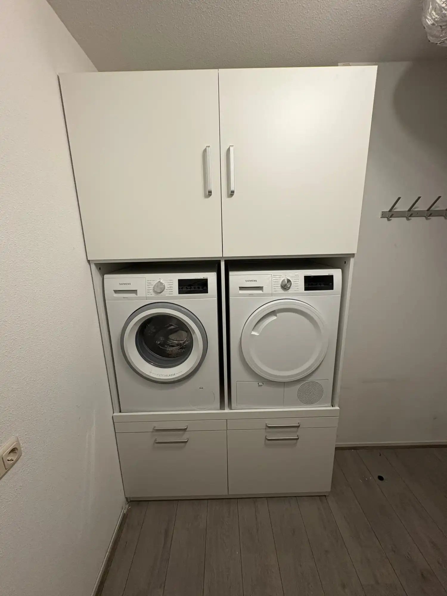 Een witte waskast met een wasmachine en droger.